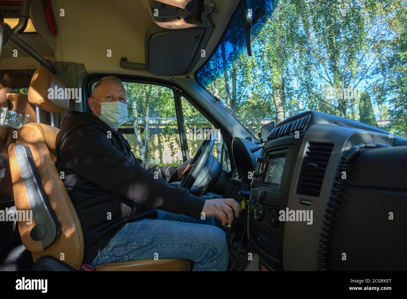 Driver in a medical mask leads a black bus Safe driving during a pandemic, protection against coronavirus. High quality photo Stock Photo