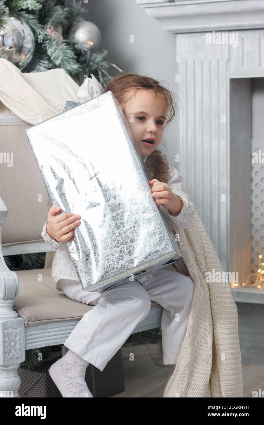 Little girl sitting in a chair with christmas box at hands Stock Photo ...