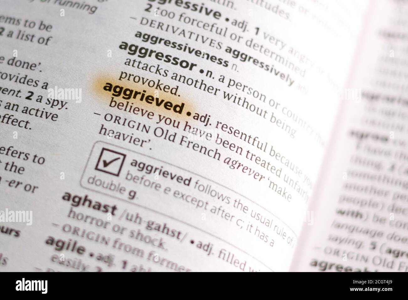 The word or phrase Aggrieved in a dictionary highlighted with marker ...