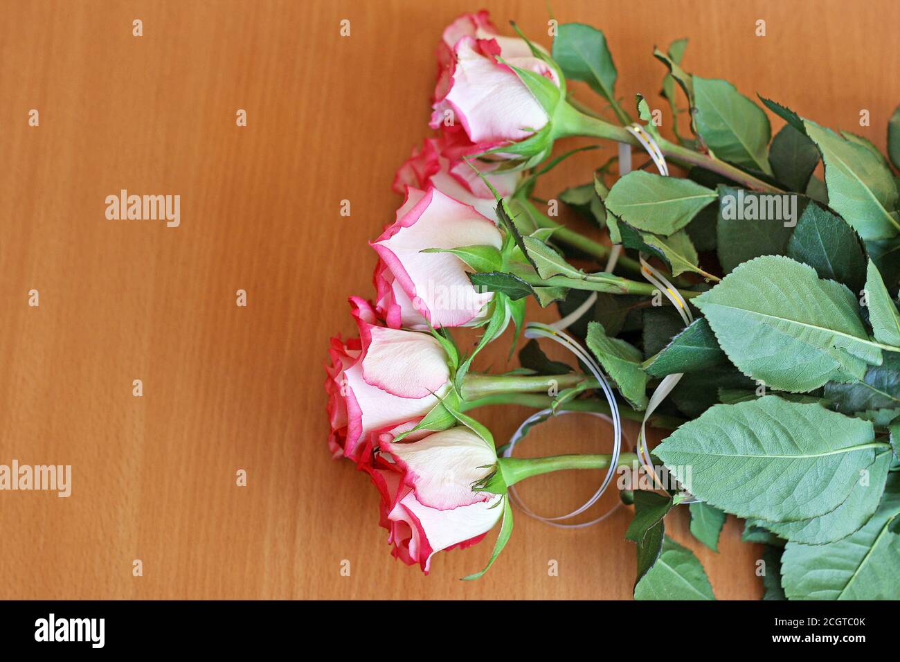 Bouquet of small pink roses, lying on the wooden surface of the table. Stock Photo
