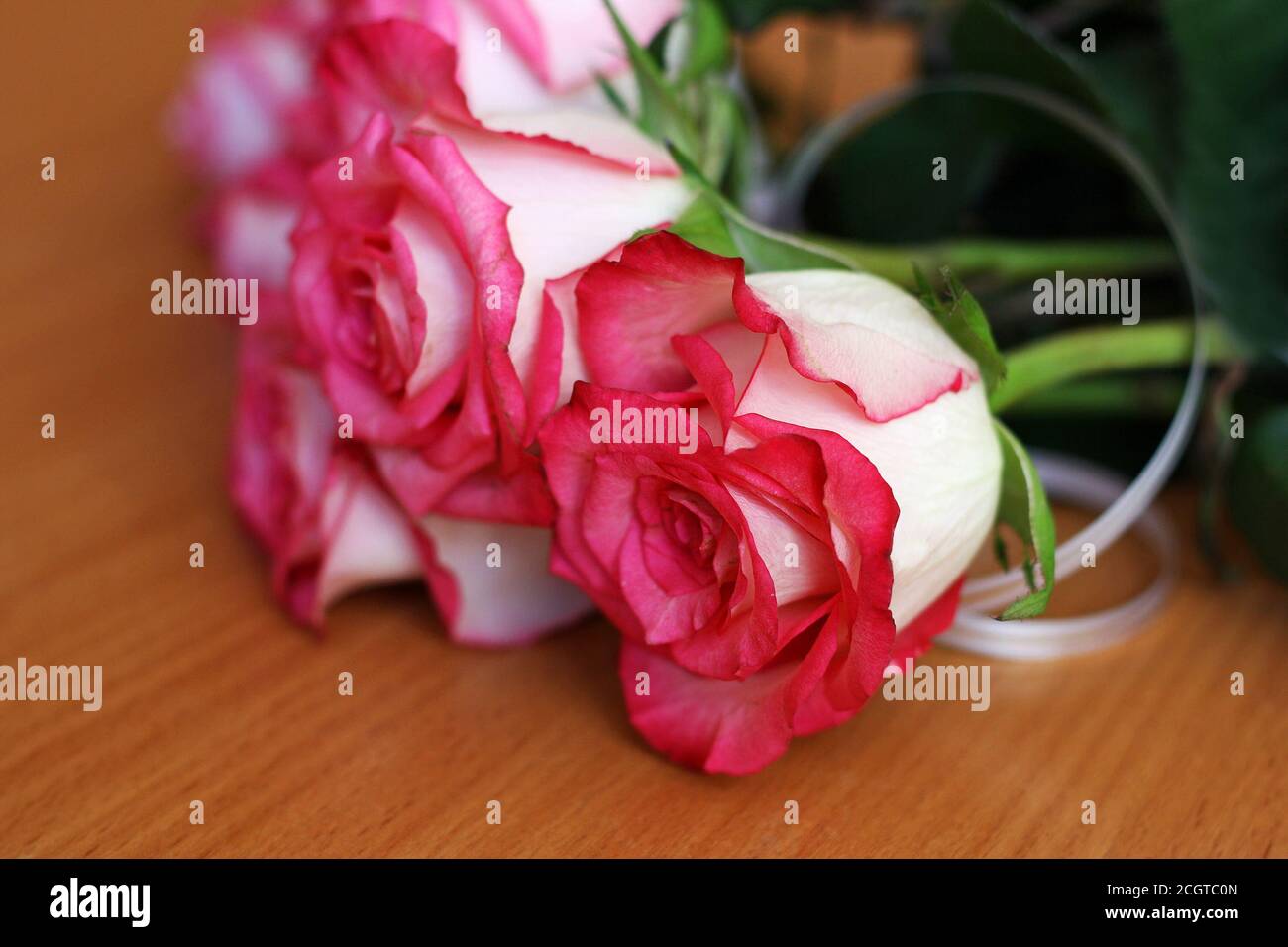 Bouquet of small pink roses, lying on the wooden surface of the table. Stock Photo