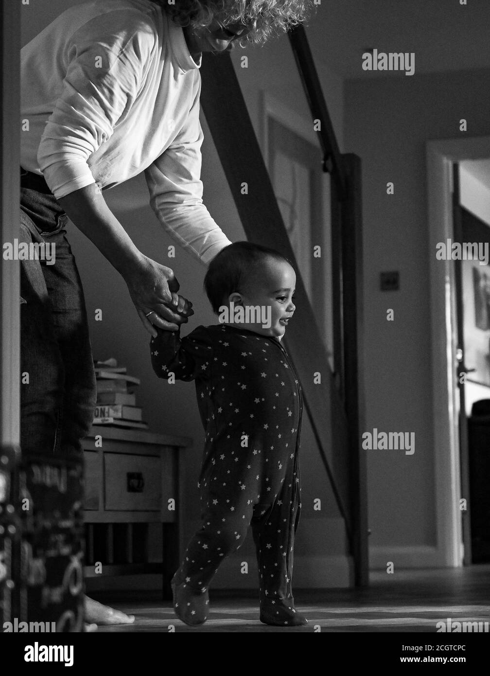 Young 10 month old baby boy learning to walk with his grandmother Stock Photo