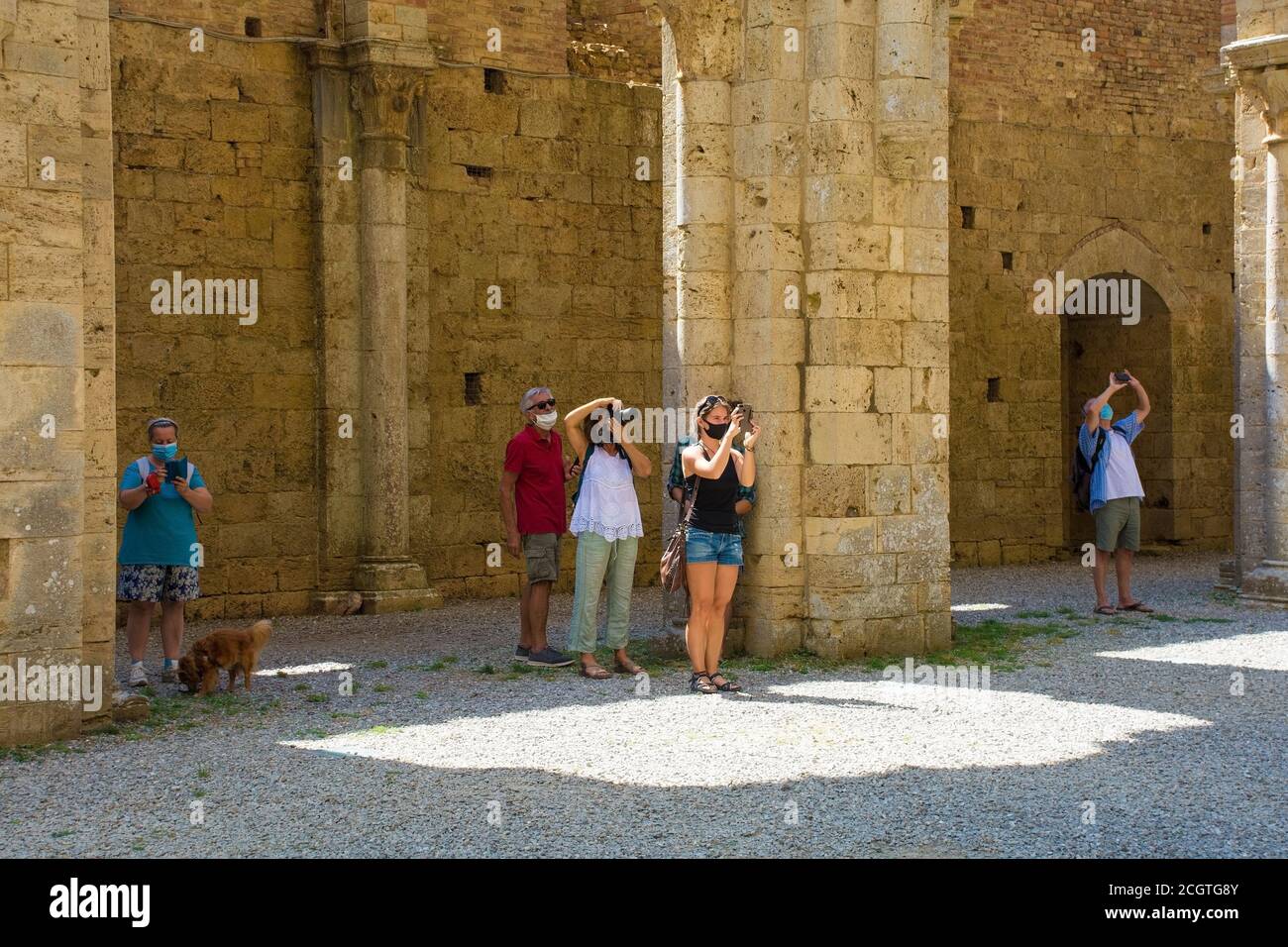Monticiano,Italy - September 7th 2020. Tourists wearing masks take photos in the historic roofless 13th century gothic cistercian abbey of San Galgano Stock Photo