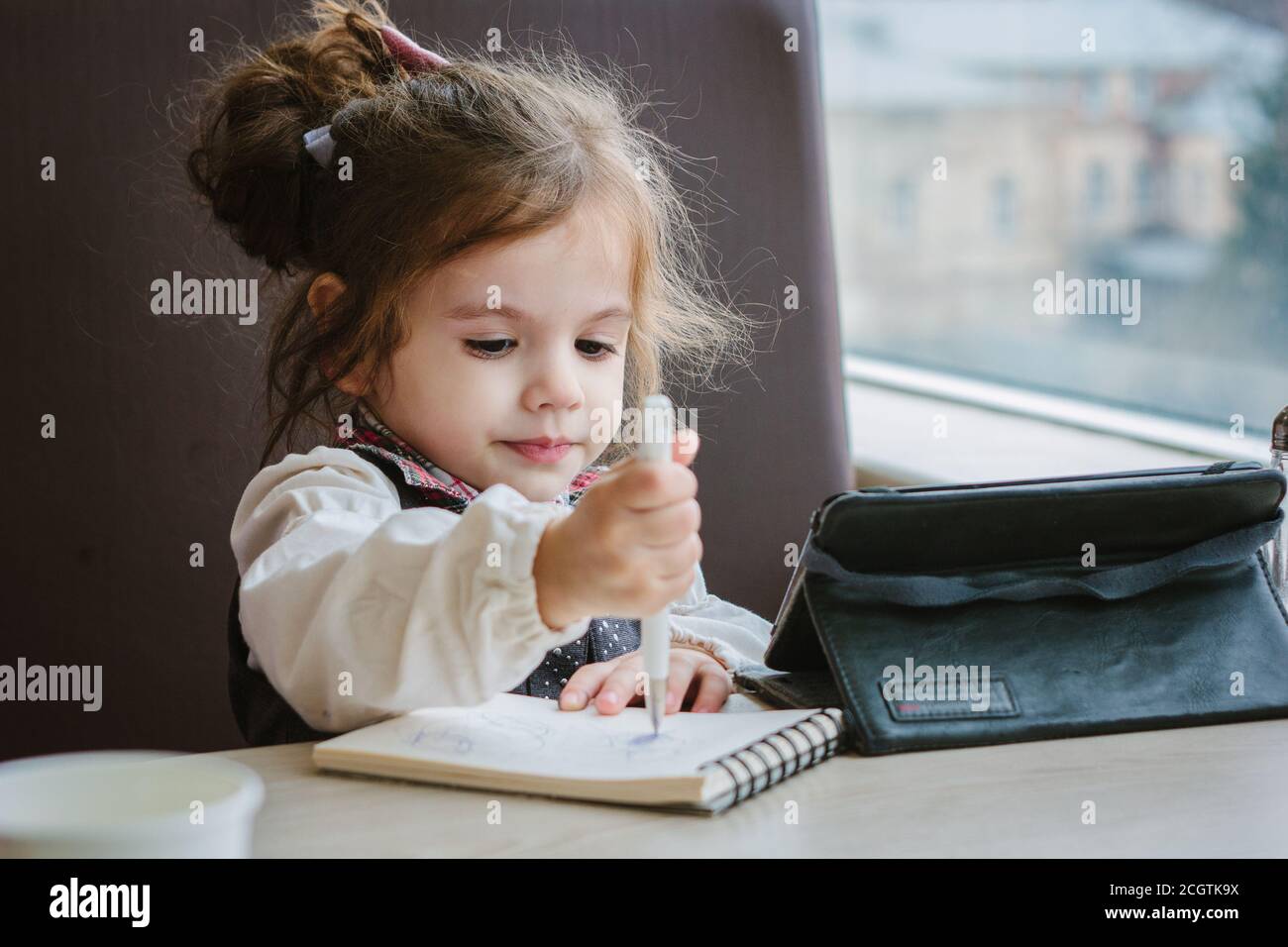 Little kid girl writing or drawing with pen in scetch book Stock Photo ...