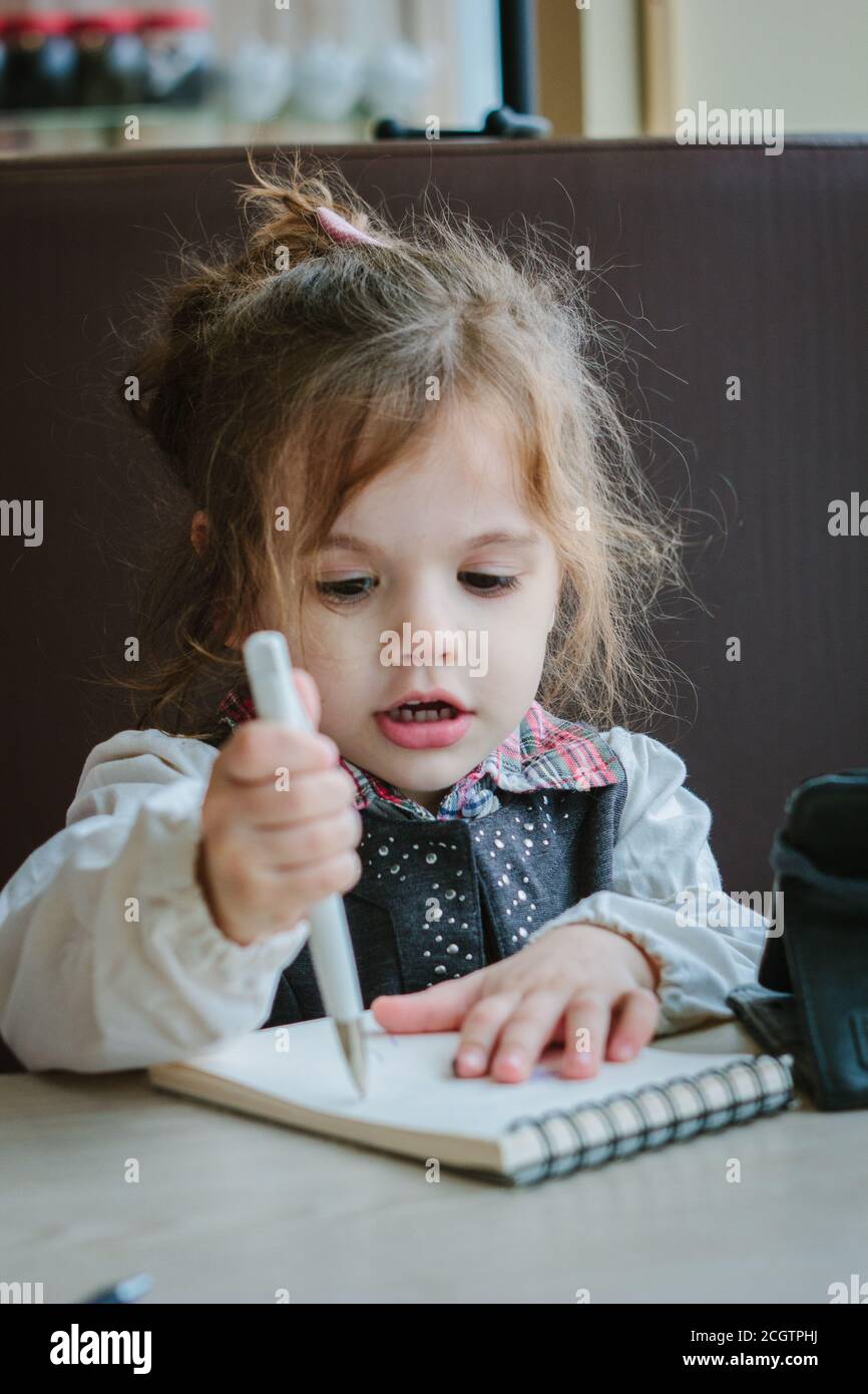 Little kid girl writing or drawing with pen in scetch book Stock Photo ...