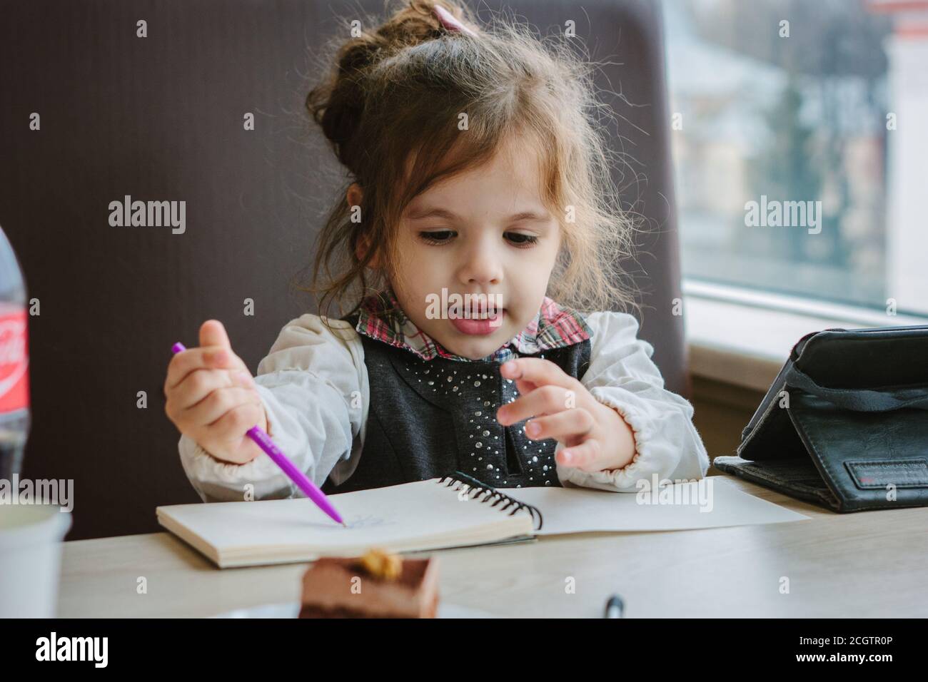 Little kid girl writing or drawing with pen in scetch book Stock Photo ...