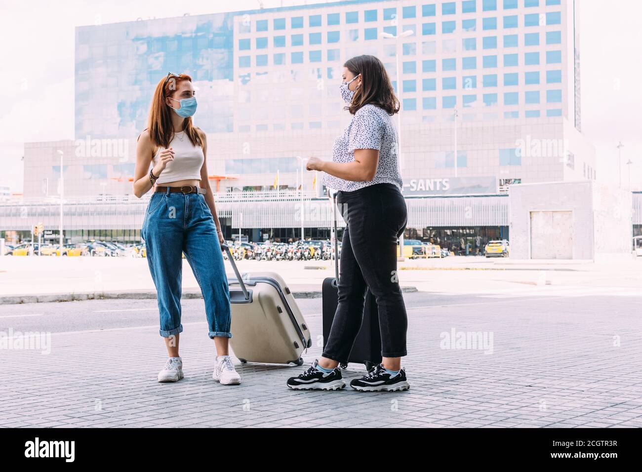 two tourists wearing face masks converse while keeping a safe distance due to covid-19 Stock Photo