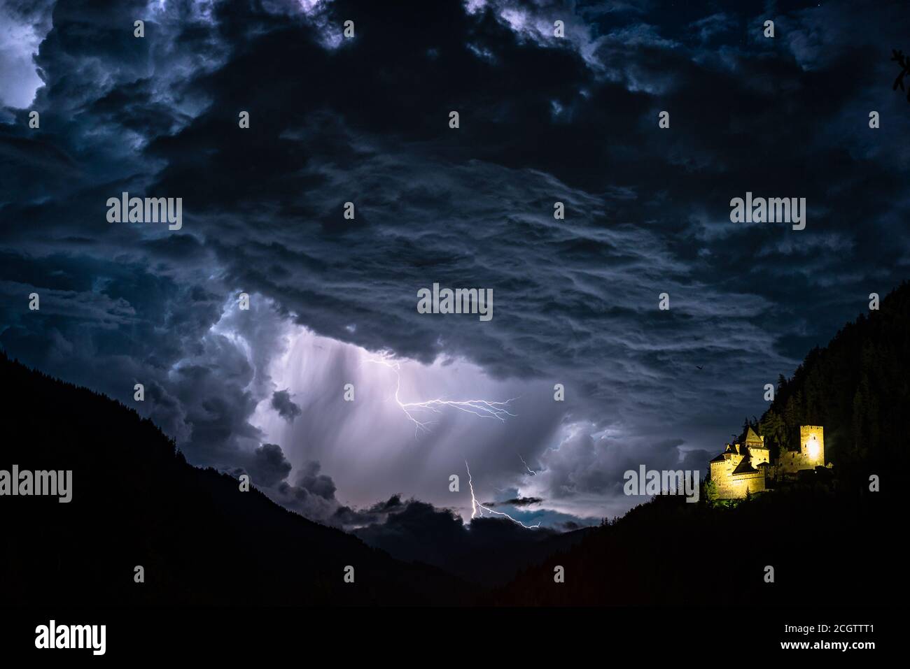 Dramatic sky with thunderstorm and lightning near a castle in the mountains Stock Photo