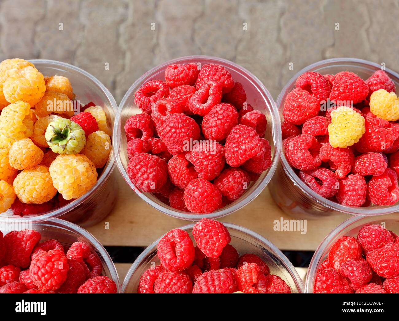 Red Andyellow Raspberry Red and yellow raspberries are collected in plastic cups and sold in ...