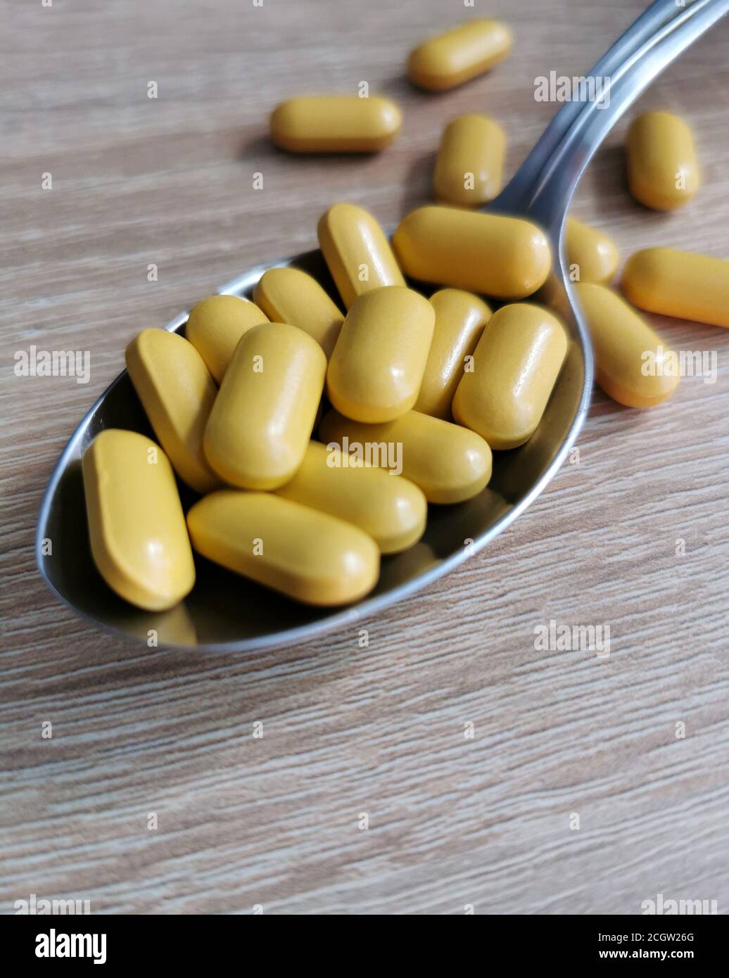 Spoon with pills, dietary supplements on wooden table. Stock Photo