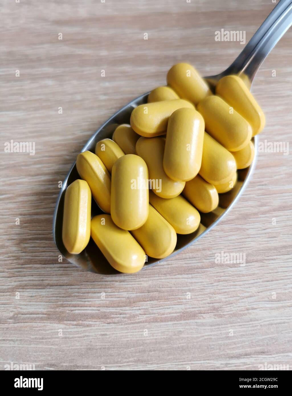 Spoon with pills, dietary supplements on wooden table Stock Photo