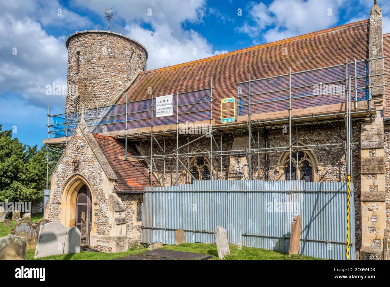 Scaffolding for repair work to the roof of the Anglo-Saxon round towered flint church of St Mary at Burnham Deepdale on the North Norfolk coast. Stock Photo