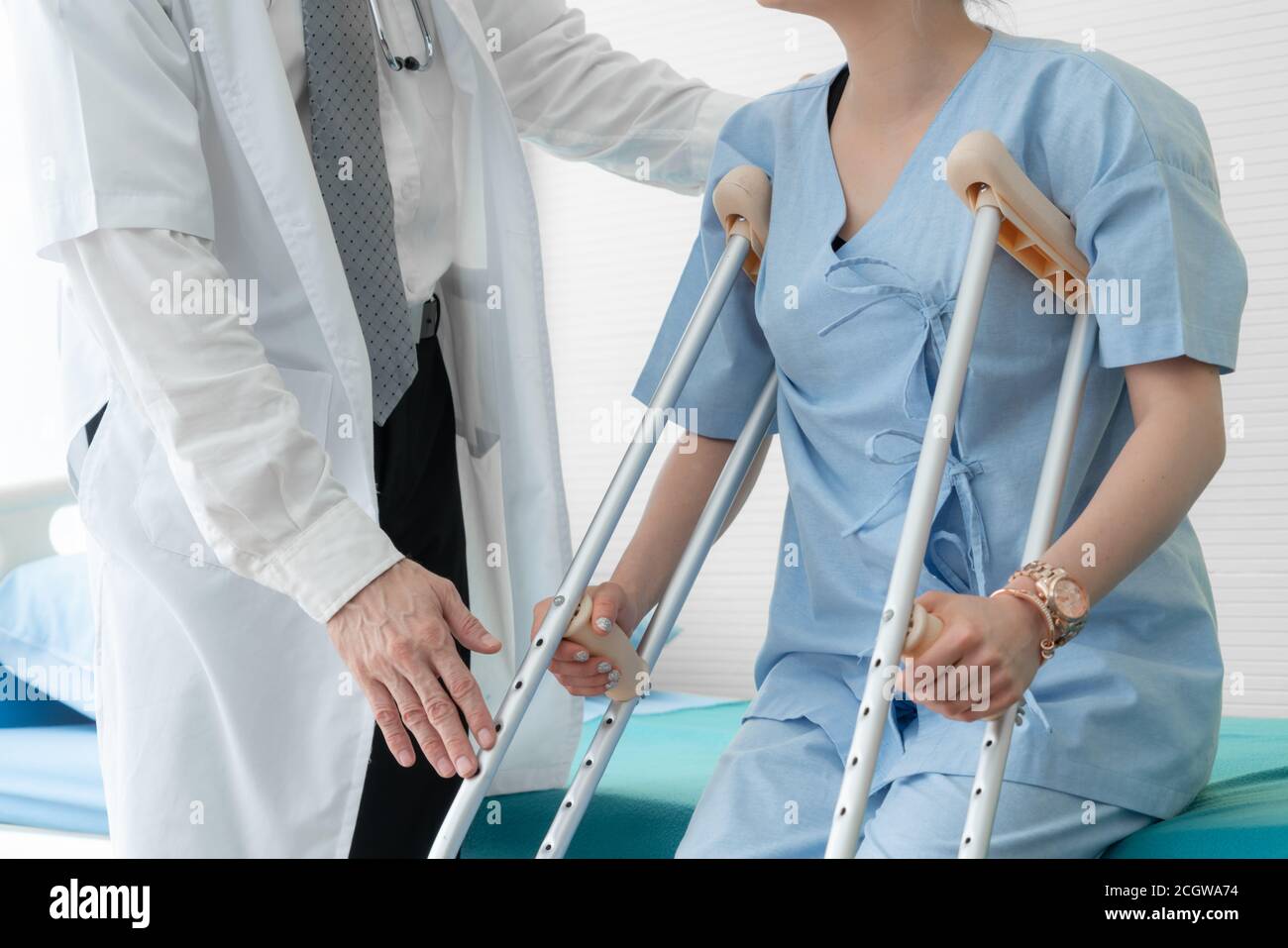 Doctor takes care of patient in crutch at hospital. Physical therapist