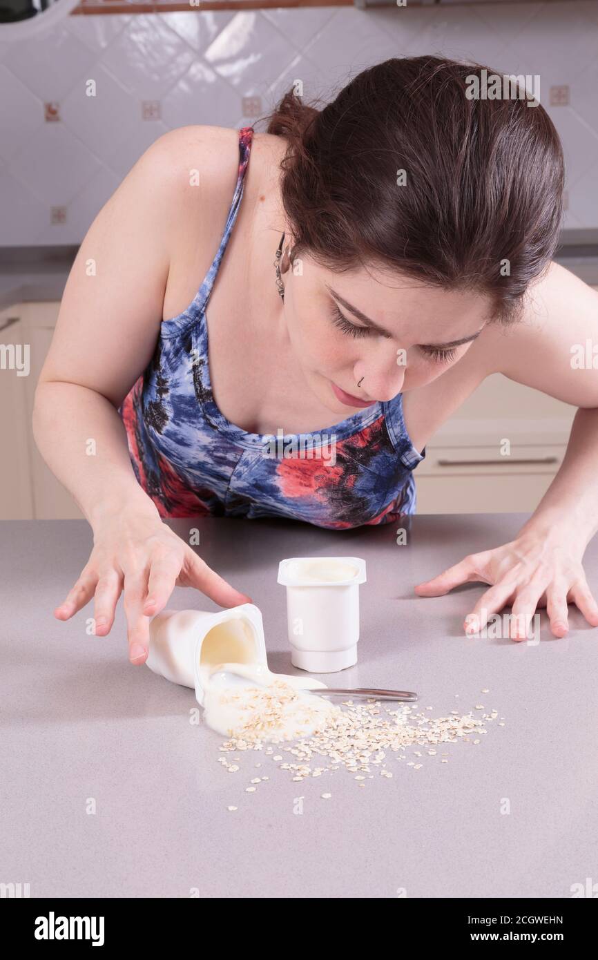 Young woman cleaning yoghurt and cereals spilt left by somebody else Stock Photo