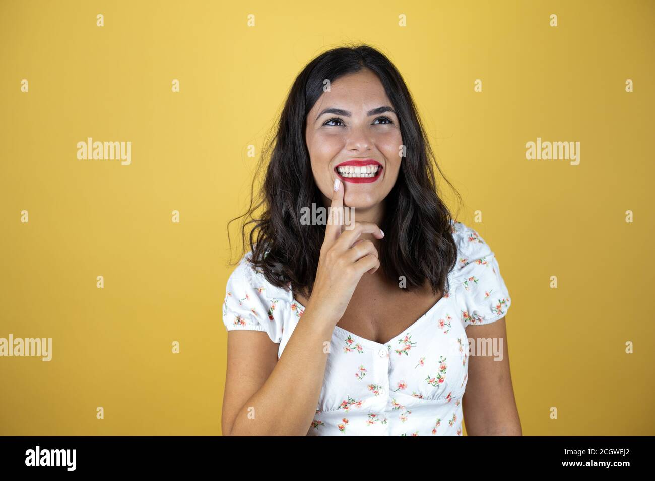 Beautiful woman over yellow background thinking and looking to the side ...