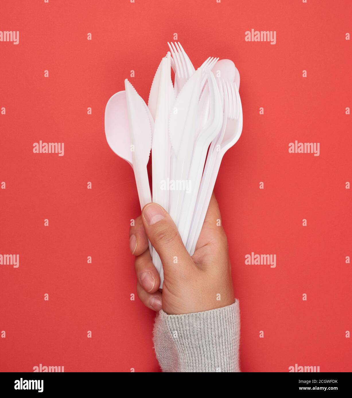 stack of plastic forks and spoons on red background, close up Stock Photo