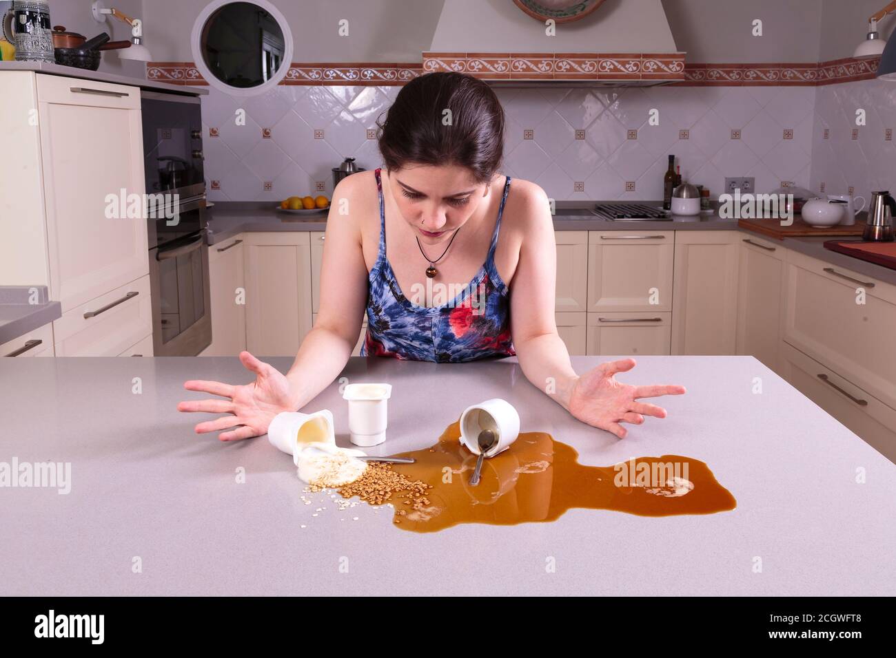 Pretty young woman looking perplexed at a mess on the counter Stock Photo