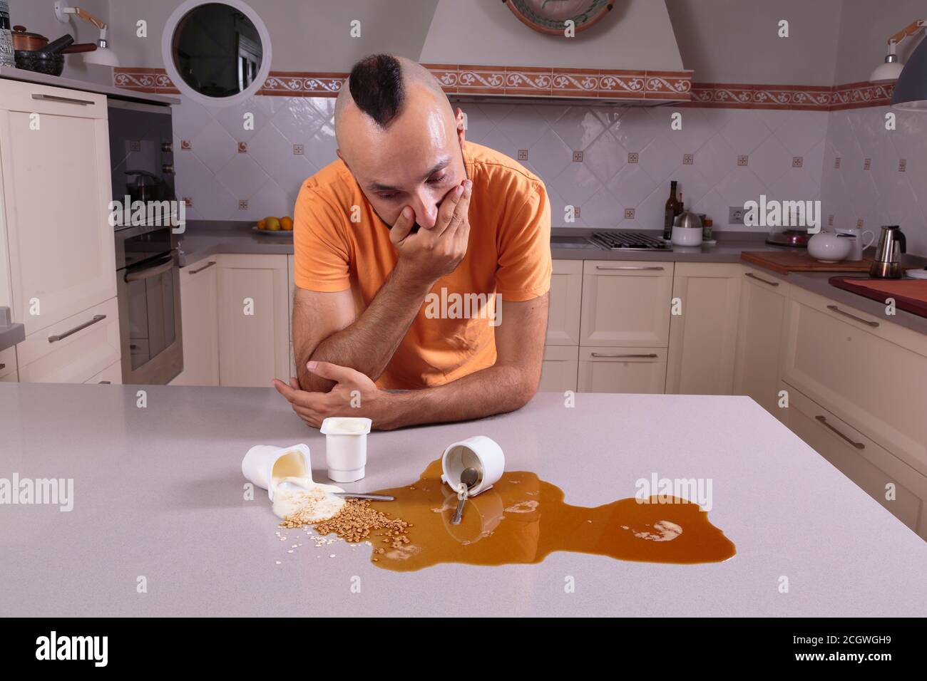 Young man looking with guilt at a mess on the counter Stock Photo