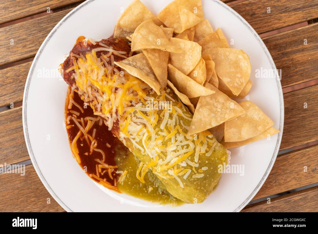 Breakfast burrito covered in cheese and sauce served with chips on the side makes a great meal. Stock Photo