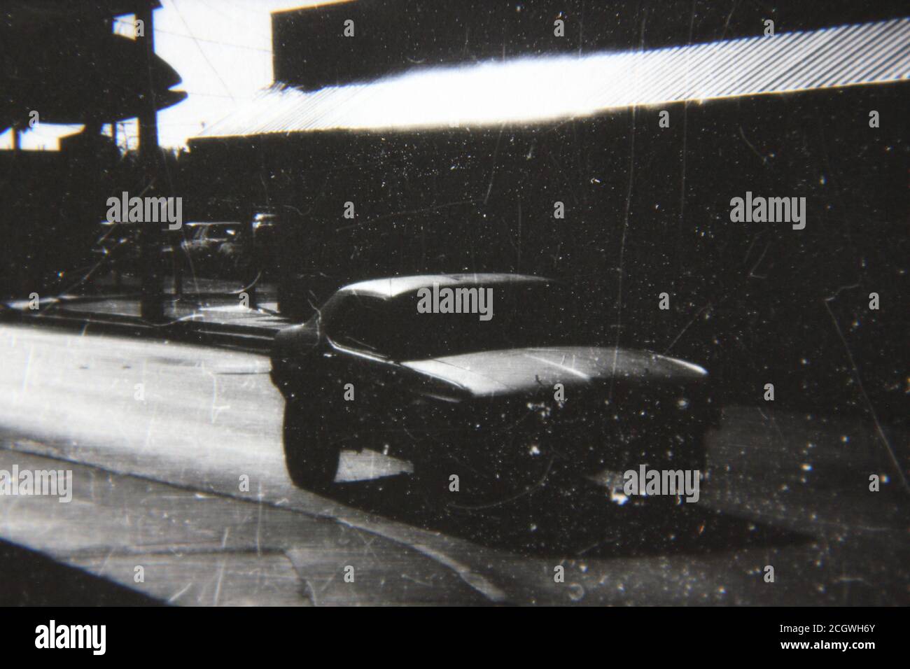 Fine 70s vintage black and white photography of a car driving down the road in the bright sunlight. Stock Photo