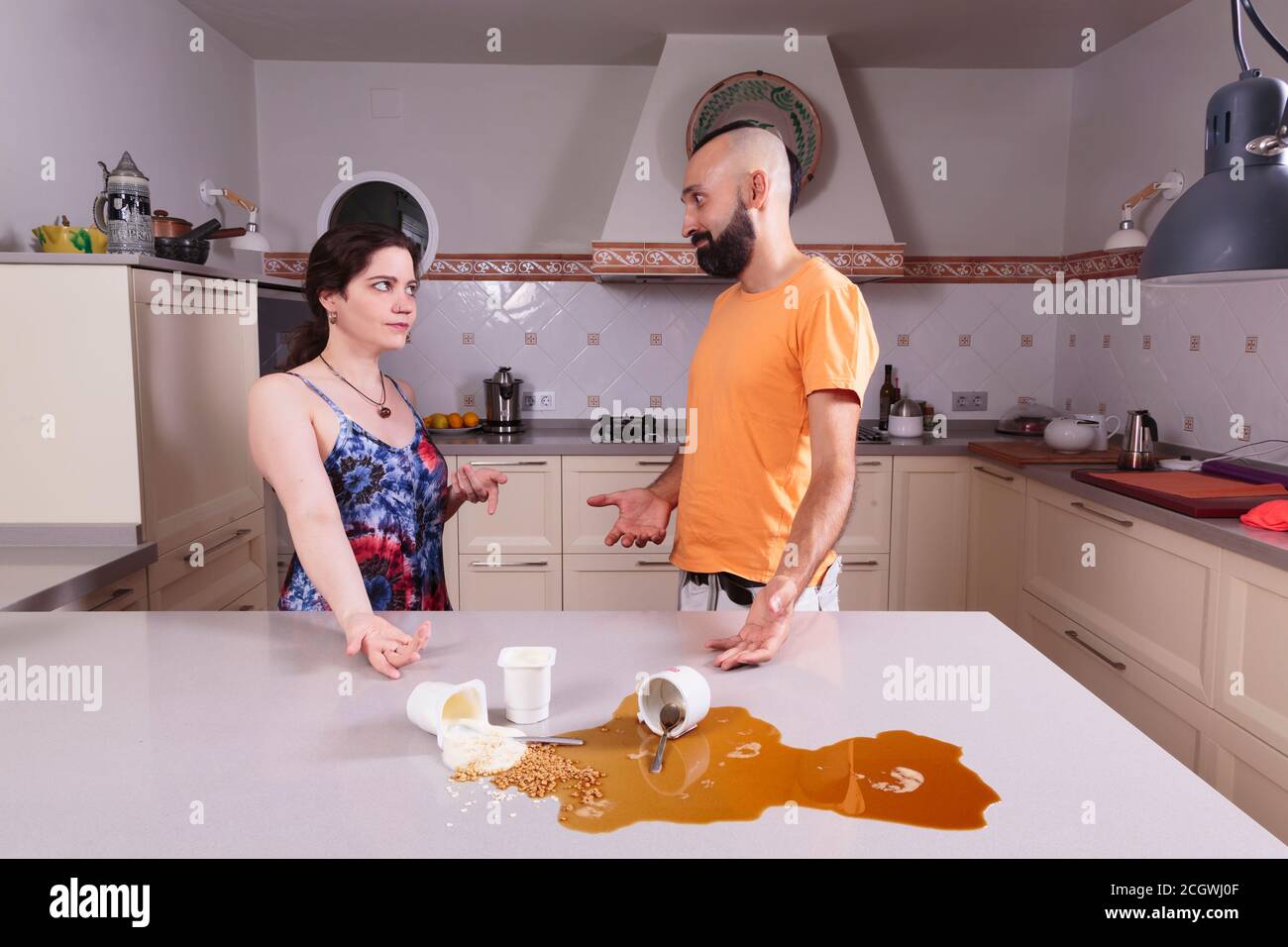 Hispanic couple arguing about the dirty kitchen counter Stock Photo