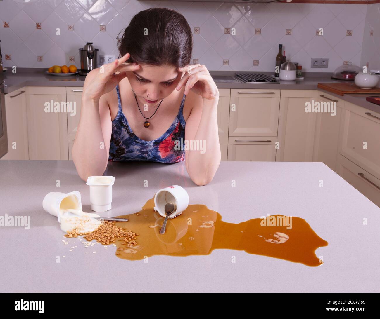 Pretty young woman upset looking at a mess on the kitchen counter Stock Photo