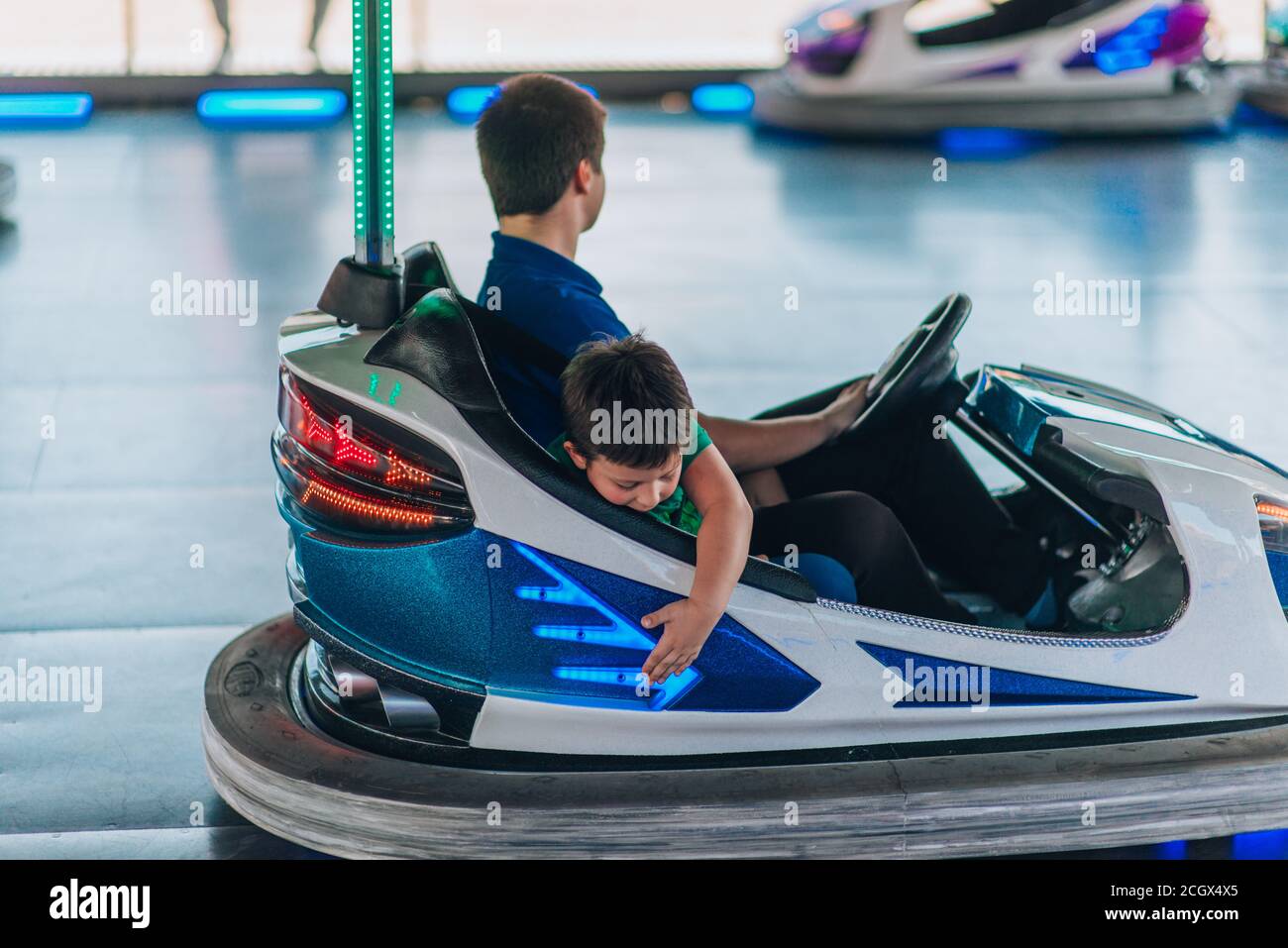 Happy young teens driving a bumper car at amusement park Stock Photo