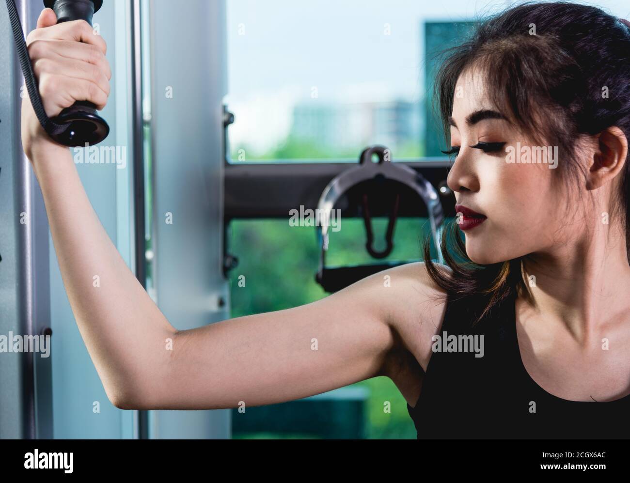 Beautiful woman exercise using machine crossover cable training workout at fitness gym Stock Photo