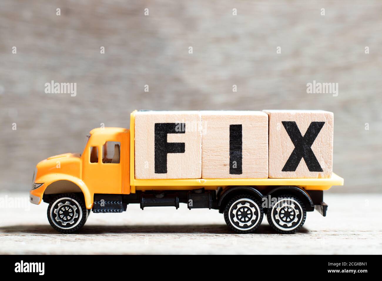 Truck hold letter block in word fix on wood background Stock Photo