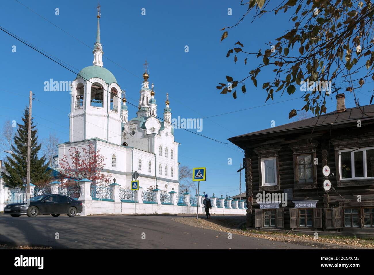 Wooden house on a village street in the background of the Assumption of the Blessed Virgin Mary Cathedral (1793) of the Yeniseisk city in the autumn a Stock Photo