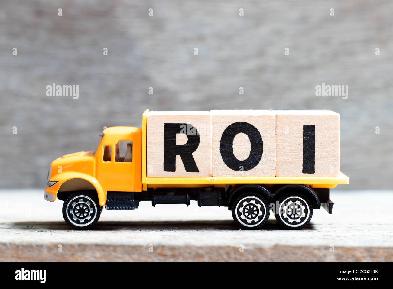 Truck hold letter block in word ROI (Abbreviation of Return on Investment) on wood background Stock Photo