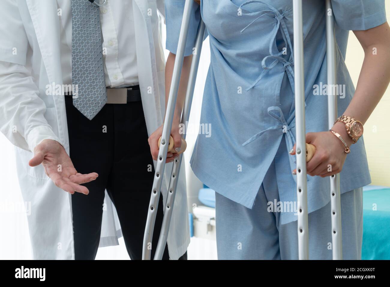 Doctor takes care of patient in crutch at hospital. Physical therapist