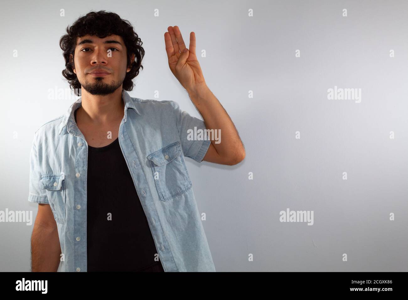 young hispanic deaf man using sign language to communicate, on a white background wearing casual clothes Stock Photo