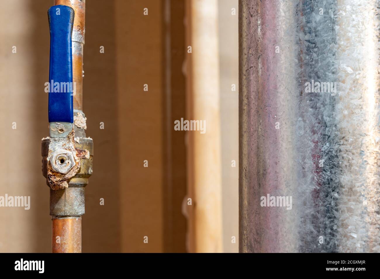 hot water line with a ball valve heavily rusted and damaged Stock Photo