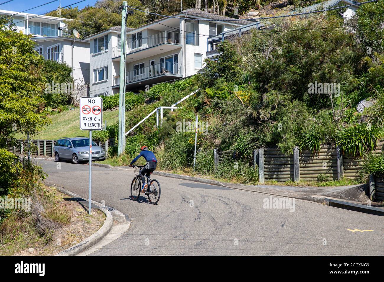 Man male cyclist riding his bike up a hill in the Sydney suburb of Whale Beach,Sydney,Australia Stock Photo