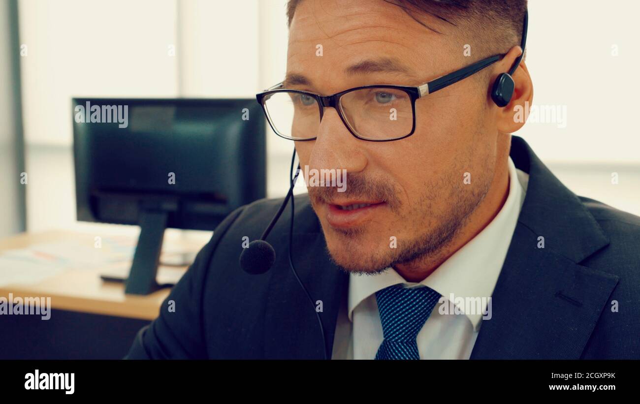 Business people wearing headset working in office to support remote customer or colleague. Call center, telemarketing, customer support agent provide service on telephone video conference call. Stock Photo