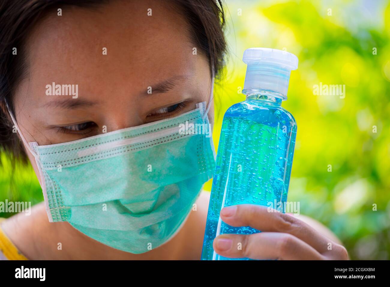 women wearing surgical face mask holding showing alcohol gel pump
