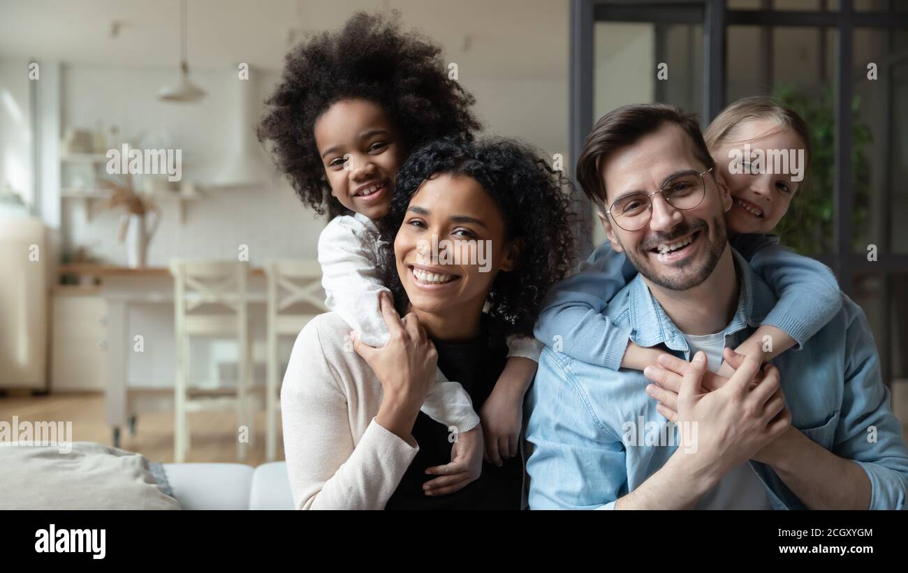 Happy multiracial couple enjoying sweet family moment with children. Stock Photo