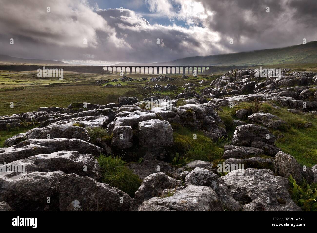 Ribblehead Viaduct on the Settle-Carlisle railway in the Yorkshire Dales National Park, seen from nearby limestone pavement rocks during a rain storm Stock Photo