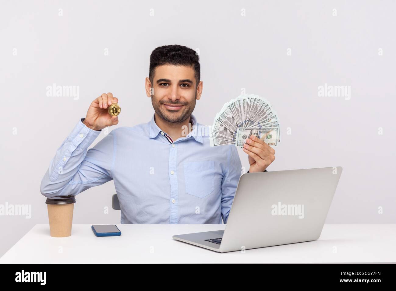 Positive elegant businessman sitting office workplace with laptop, smiling  holding money dollars and golden bitcoin btc, cryptocurrency investment. in  Stock Photo - Alamy