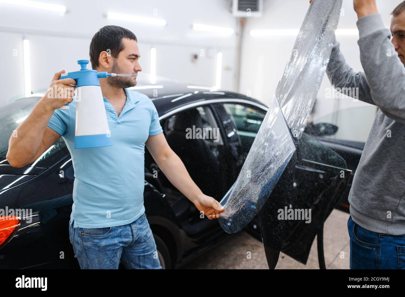 Male worker with spray wetting car tinting Stock Photo Alamy