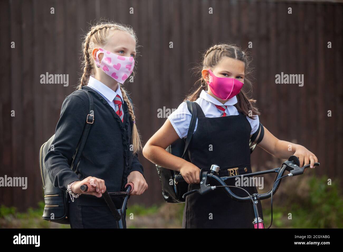 two 10 year old schoolgirls in school uniform and wearing face masks Stock Photo