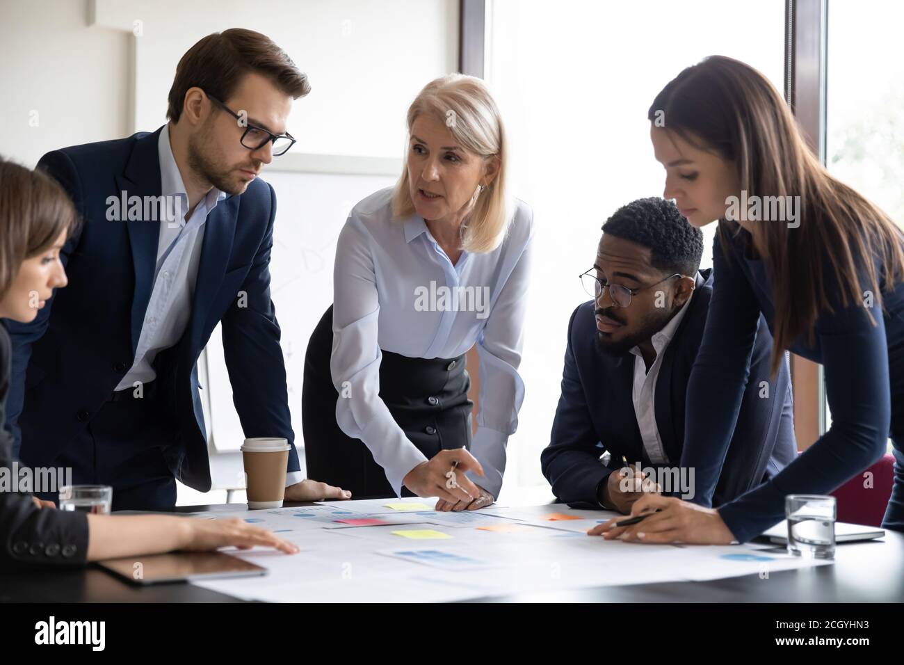 Focused diverse businesspeople discuss paperwork at meeting Stock Photo