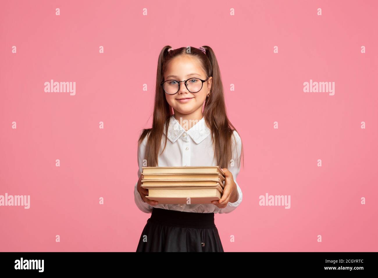School and library concept. Little girl in school uniform and glasses holds books Stock Photo