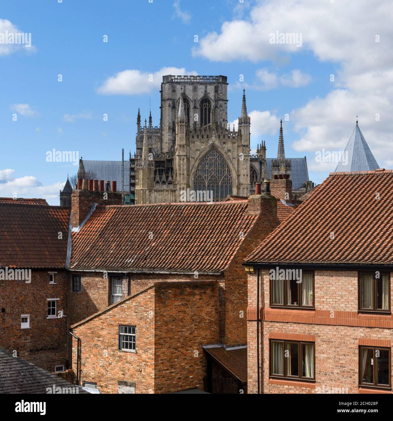 York Minster towering over modern & historic brick houses in scenic residential urban city (view over red rooftops) - North Yorkshire, England, UK. Stock Photo