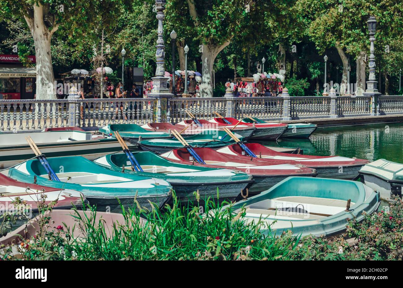 Selective focus on empty rowing boats in Plaza de España with tourists wearing mask in the background.  Covid-19 c Stock Photo