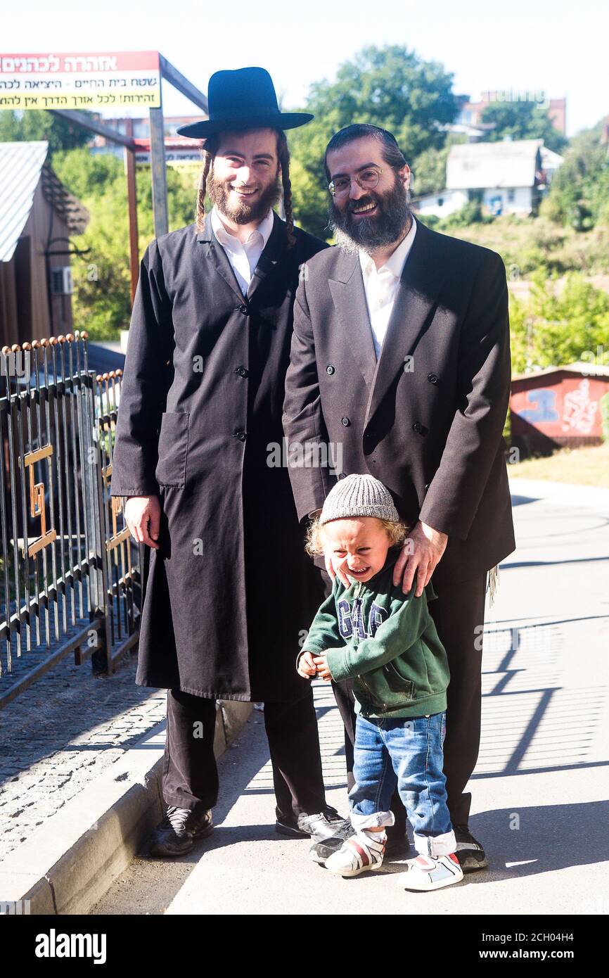 Two smiling Hasidim (hasidic pilgrims) in Uman (Ukraine) w/Jewish kid whose mother asked to photograph her son w/them b4 Rosh-ha-Shana (New Year). Stock Photo