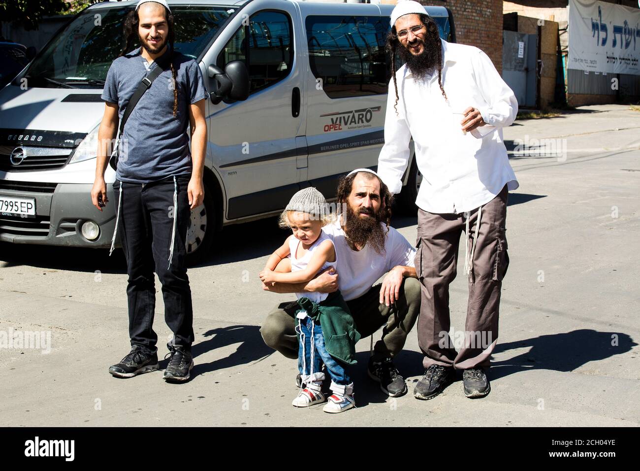 Three smiling Hasidim (hasidic pilgrims) in Uman (Ukraine) w/Jewish kid whose mother asked to photograph her son w/them b4 Rosh-ha-Shana (New Year). Stock Photo