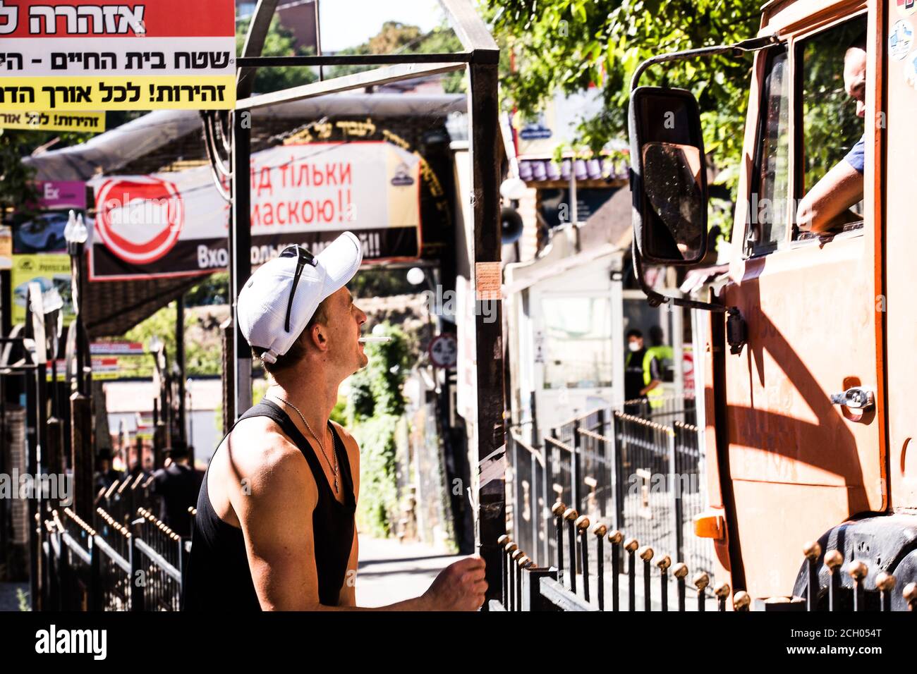 Two workers, one of them a truck driver, former classmates, talk on Pushkin str in Uman (Ukraine) near memorial of Zaddik Nachman attended by Hasidim. Stock Photo