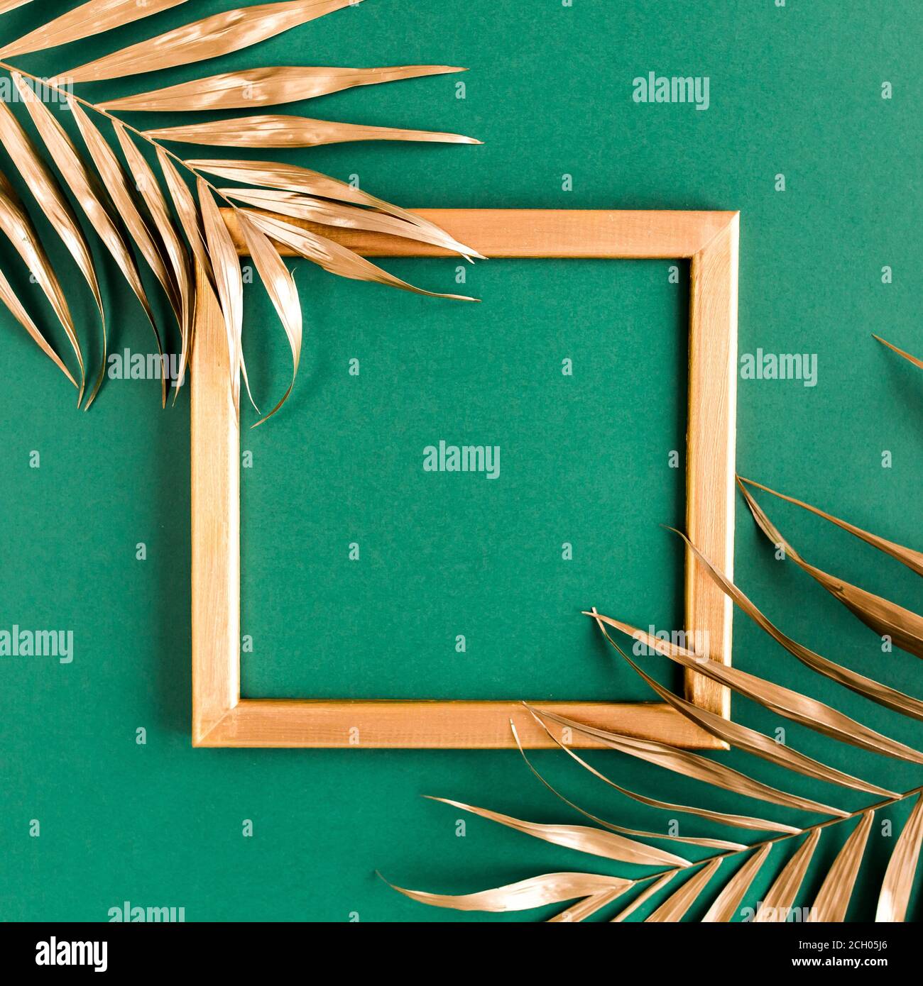 Gold tropical palm leaves and photo frame on green background. Flat lay ...